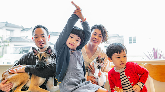 Une famille de quatre personnes, dont deux enfants, pose joyeusement avec leur chien dans un cadre pittoresque.